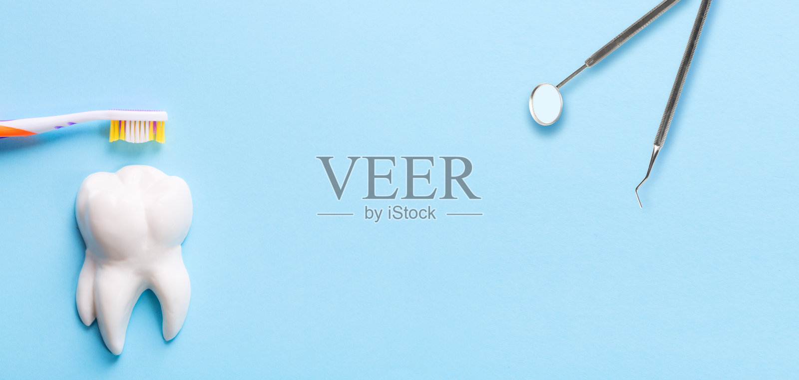 专业钢制牙科器械,近白牙模型镜面,浅蓝色背景,有自由空间的牙刷。牙齿保健和牙齿保健概念。照片摄影图片