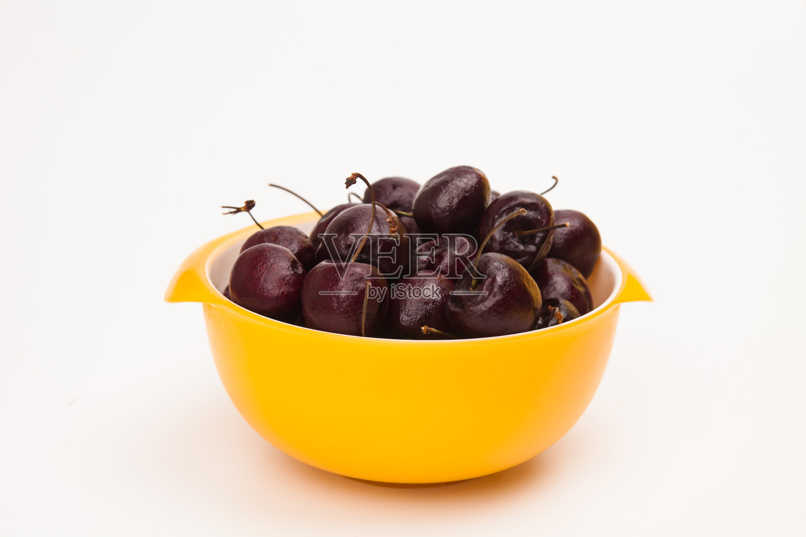 新鲜的红樱桃放在黄色的碗里照片摄影图片