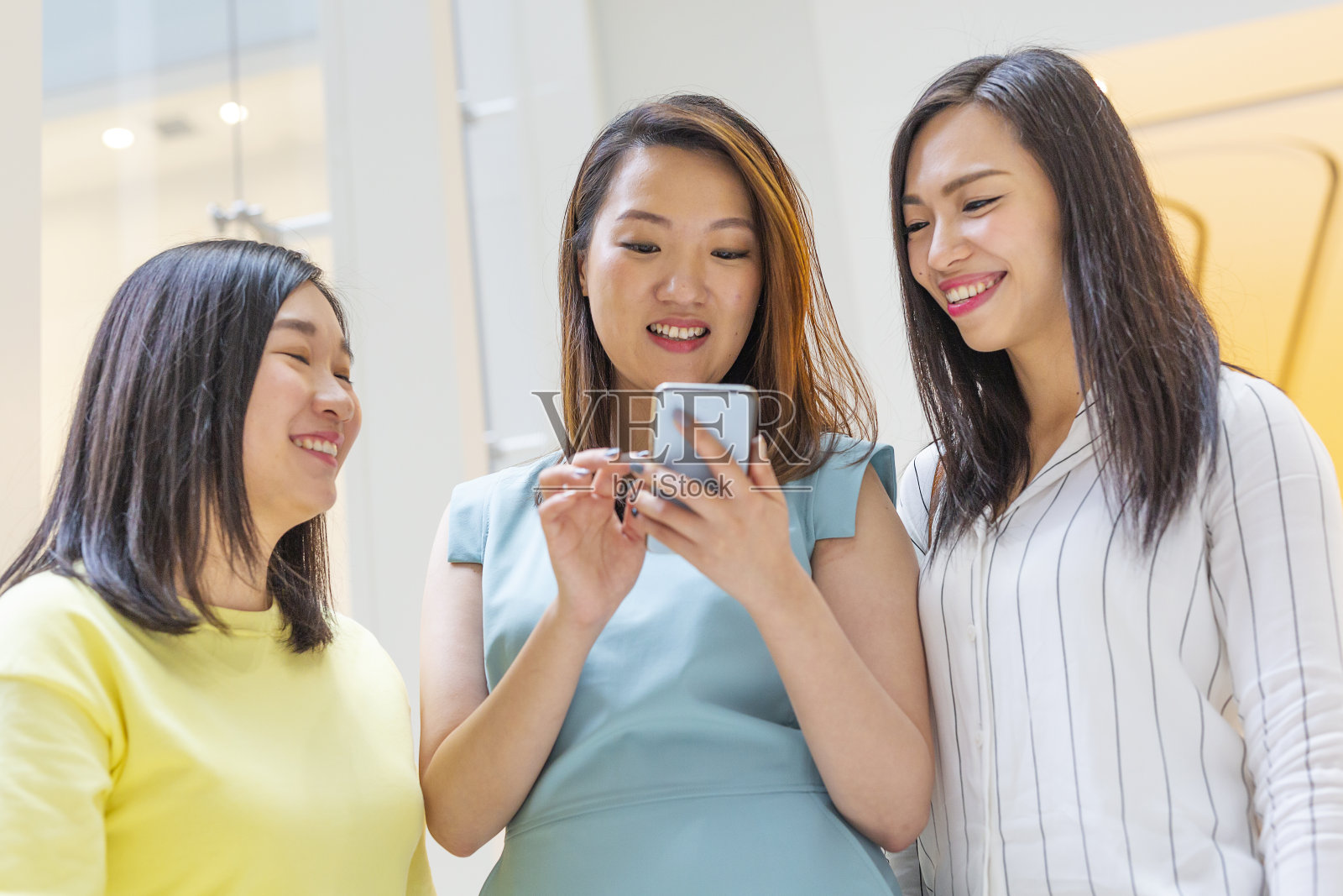 一群快乐的亚洲女性朋友在购物中心使用手机照片摄影图片