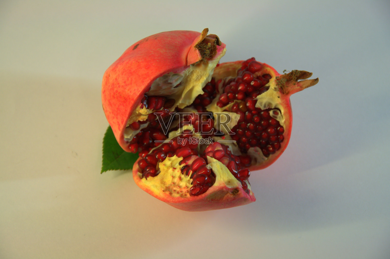 成熟的石榴被切开,露出了它自己的谷粒。照片拍摄于白色背景。照片摄影图片