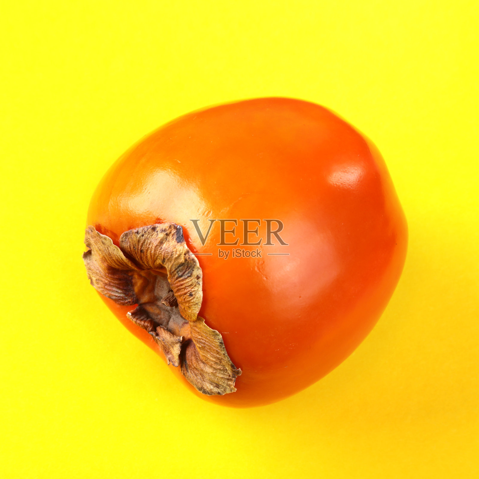 新鲜的异国水果柿子上有黄色的背景。水果的背景。前视图。照片摄影图片