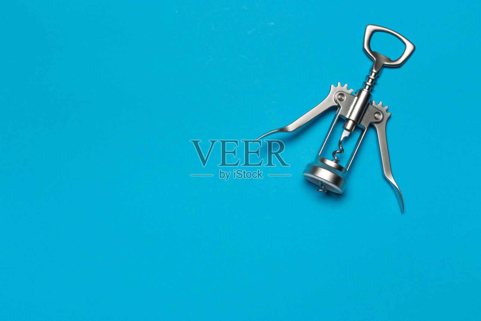 旧的磨损镀铬翼螺旋瓶塞背面上的蓝色背景照片摄影图片