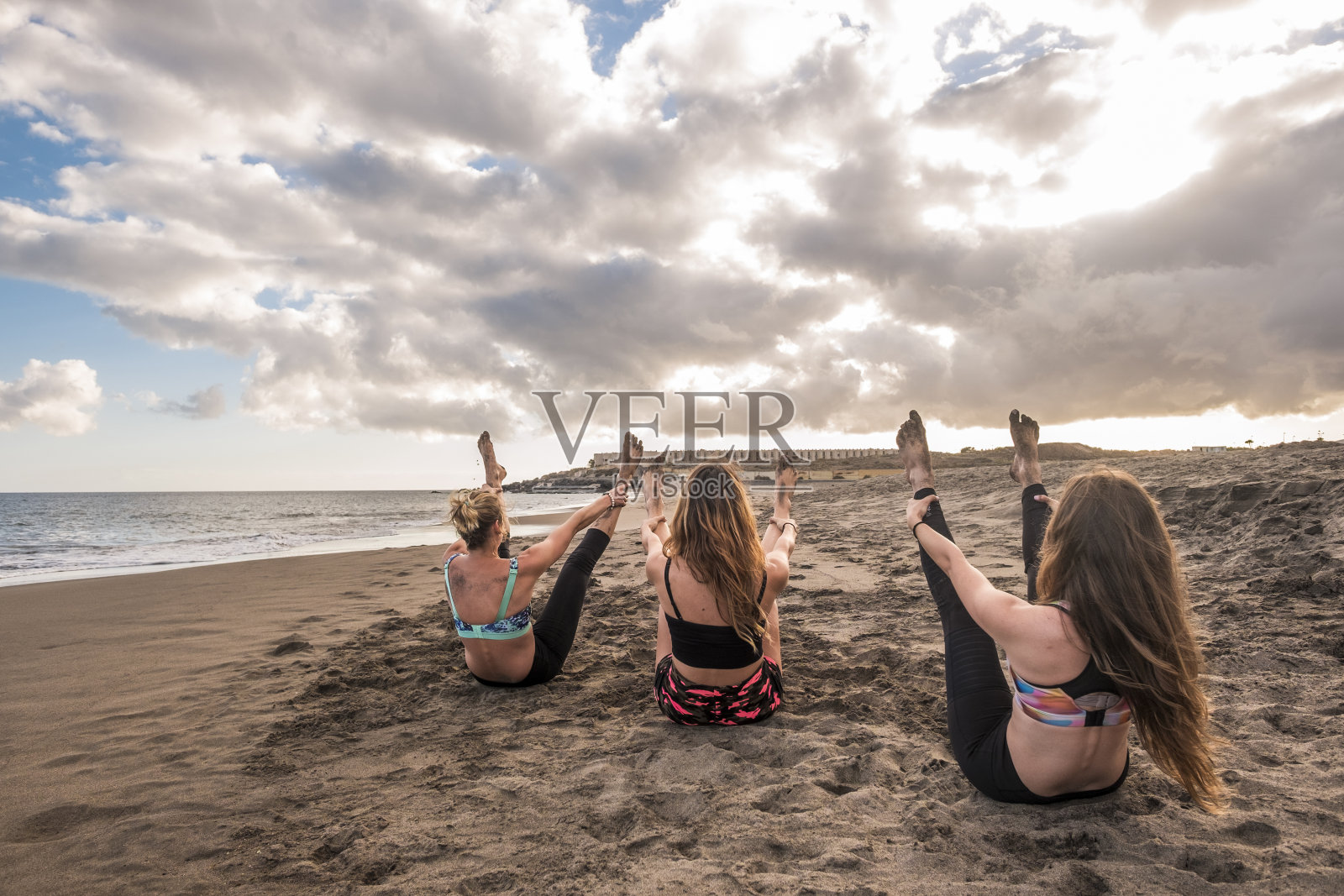 史诗图像与年轻漂亮的女人做锻炼和普拉提健身运动在海滩上在一个惊人的日落。为快乐的人们享受生活方式和热带风情照片摄影图片