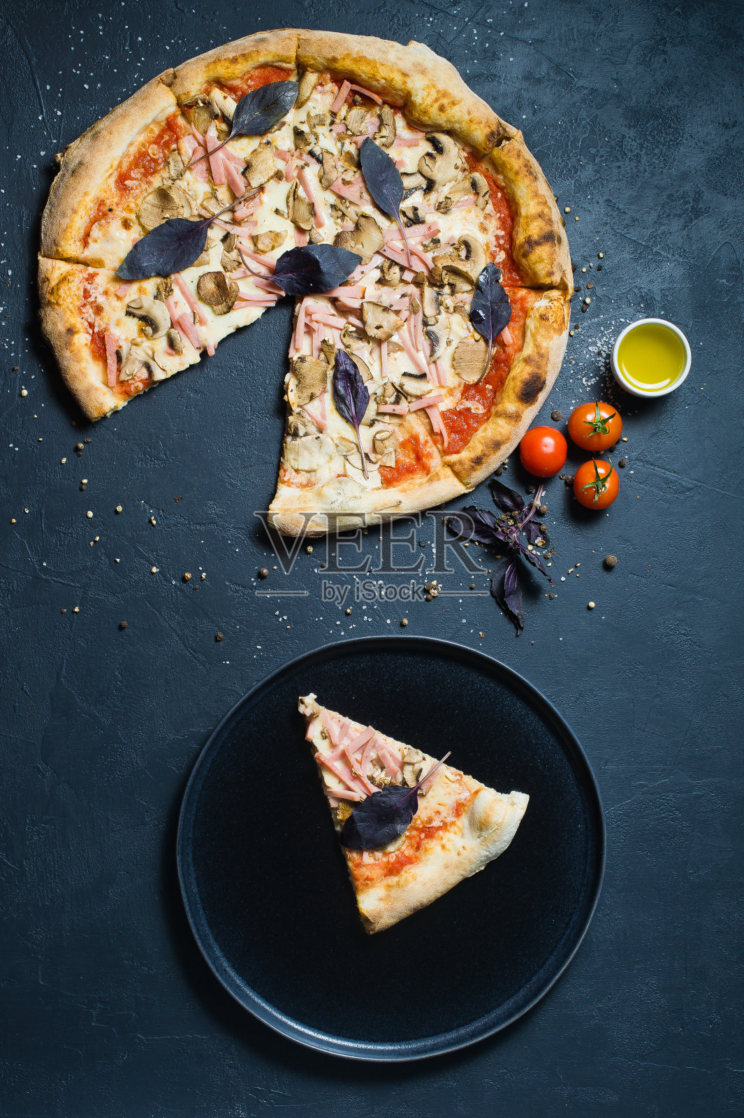 一片披萨放在一个黑色的盘子里。照片摄影图片