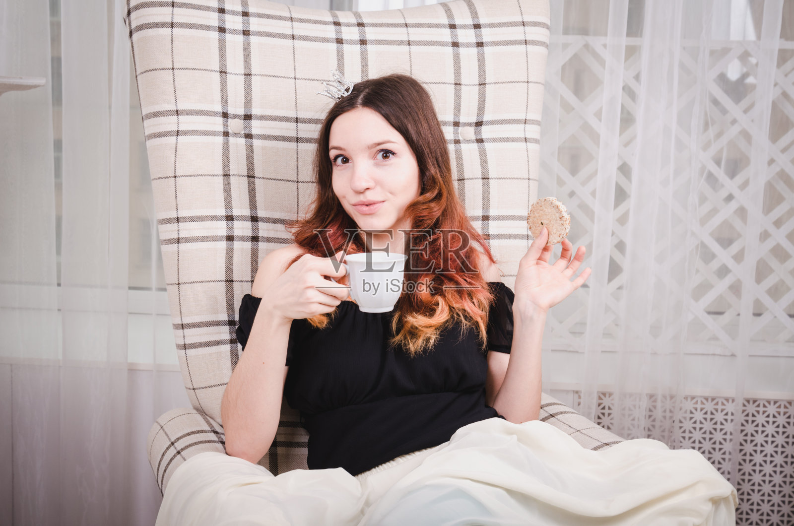 美丽美丽的公主,一头卷发,戴着皇冠,穿着绿色紧身衣,喝着英国茶照片摄影图片