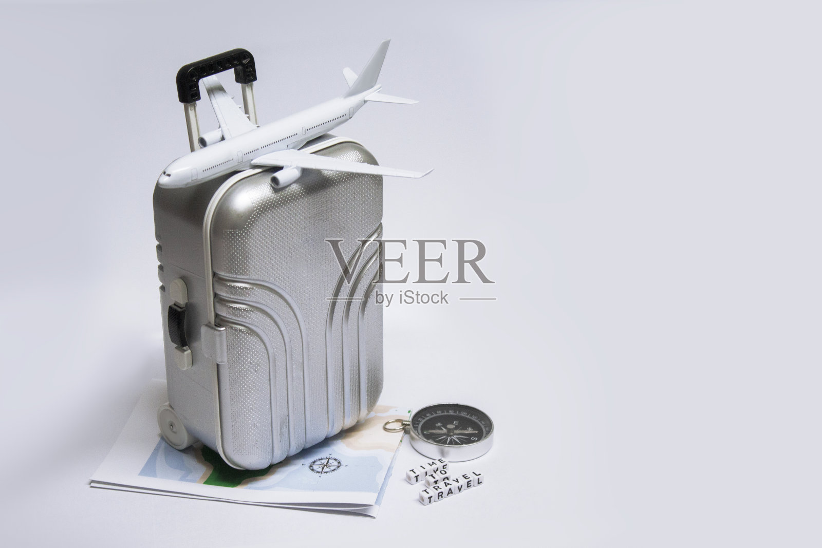 时间旅行。在一个明亮的背景上有飞机,手提箱,指南针和地图的旅游想法。关于飞行主题的概念。照片摄影图片