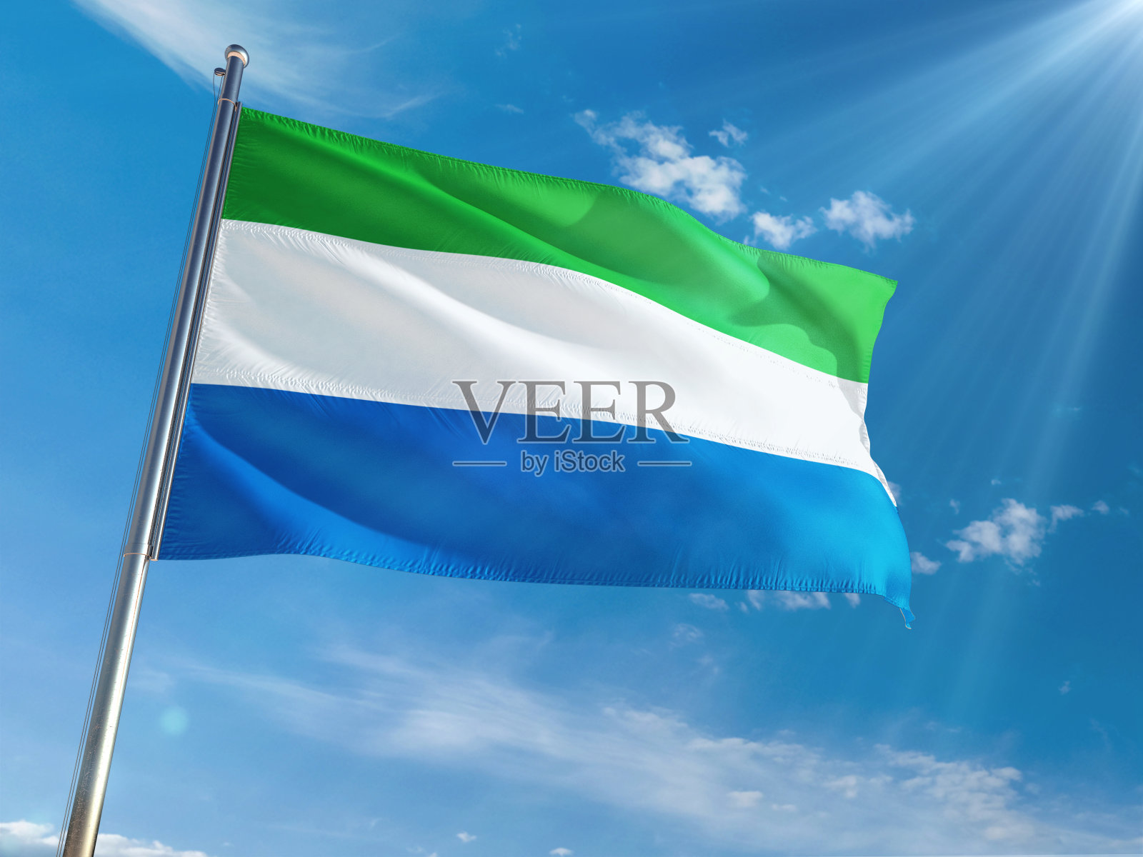 在晴朗的蓝天背景下,塞拉利昂国旗在旗杆上飘扬。高清晰度照片摄影图片