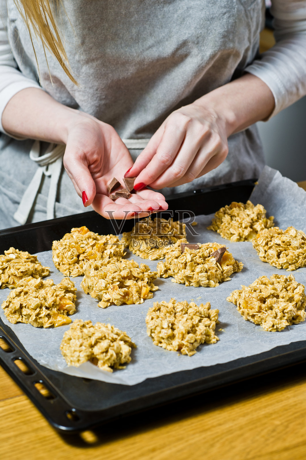 厨师正在做饼干,把生面团铺在托盘上。侧视图,黑色背景,厨房照片摄影图片