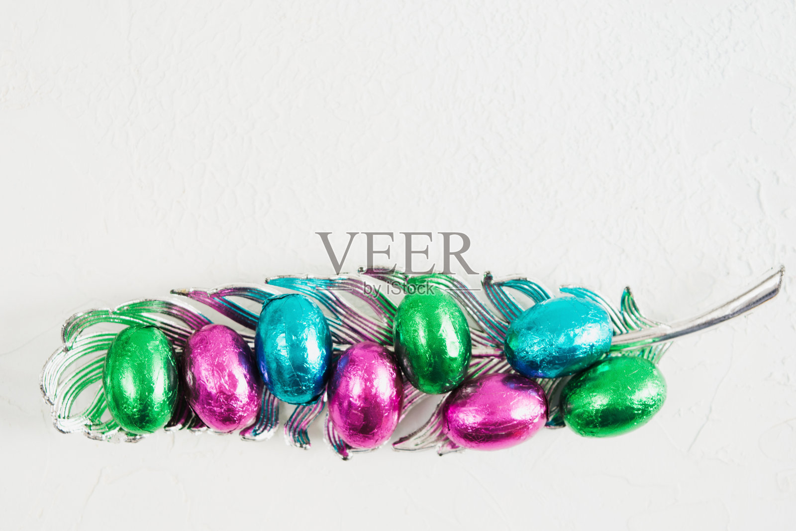 五彩缤纷的复活节巧克力蛋在闪闪发光的羽毛装饰包装照片摄影图片