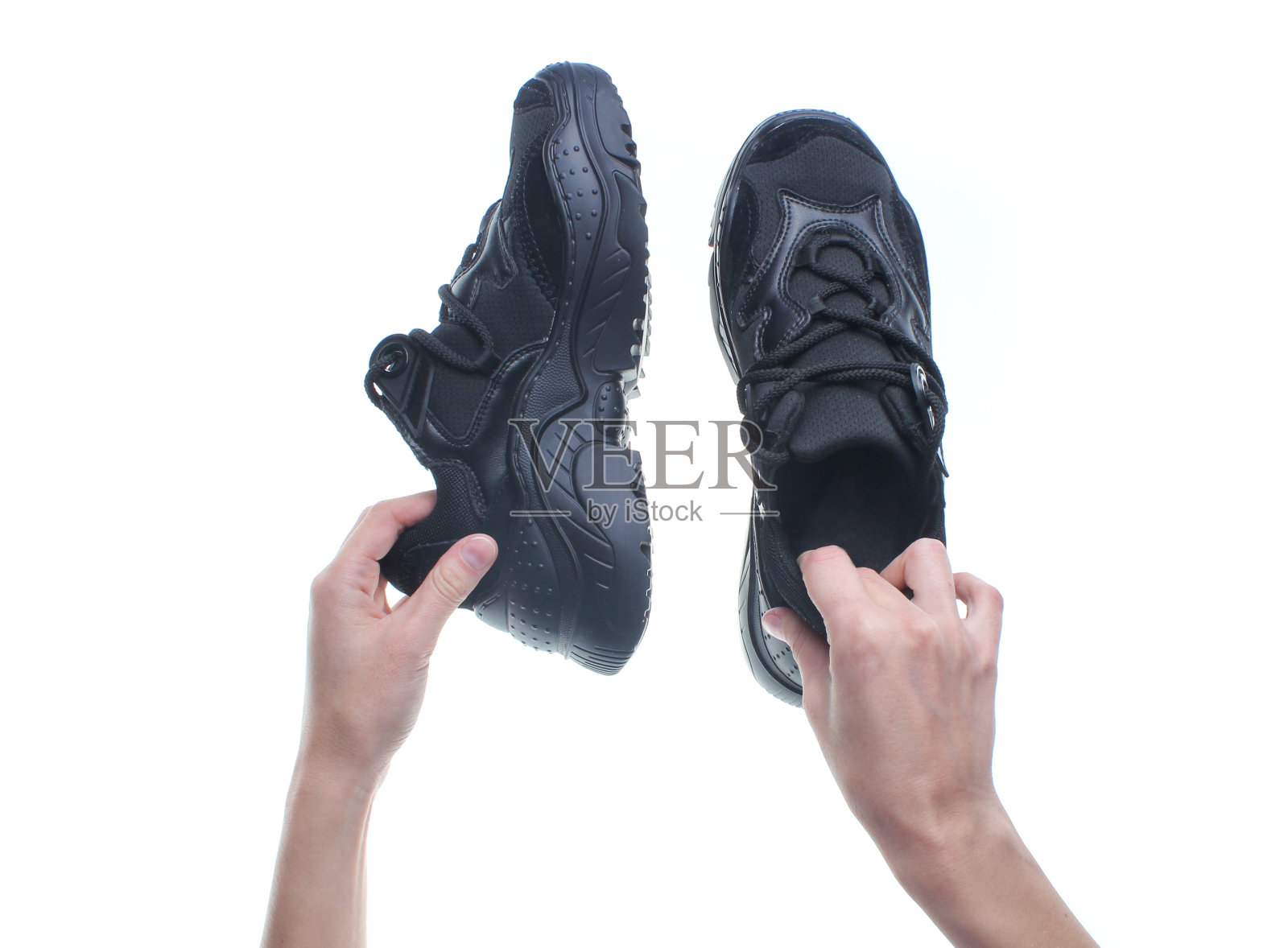 手握黑色运动鞋孤立的白色背景。前视图。照片摄影图片