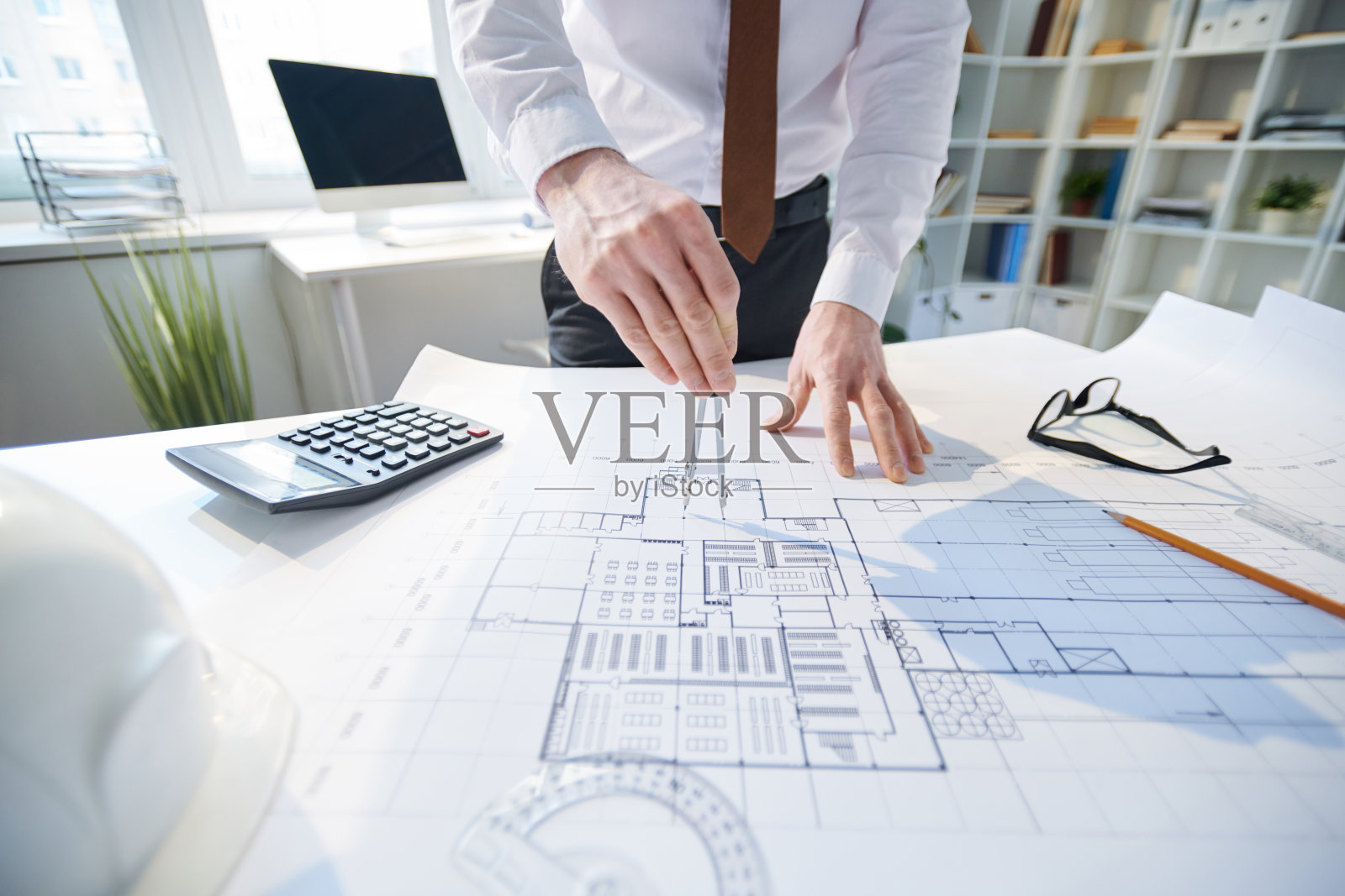 不认识的工程师在正装靠在桌子上,使用一对指南针设计住宅项目的特写照片摄影图片