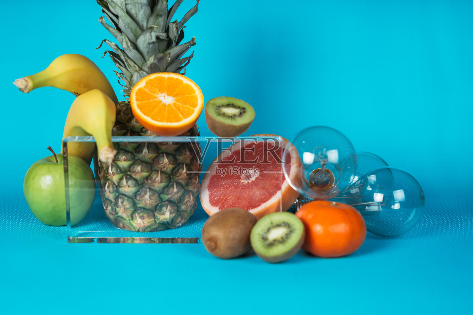 蓝色背景上有不同种类的水果和灯泡。照片摄影图片