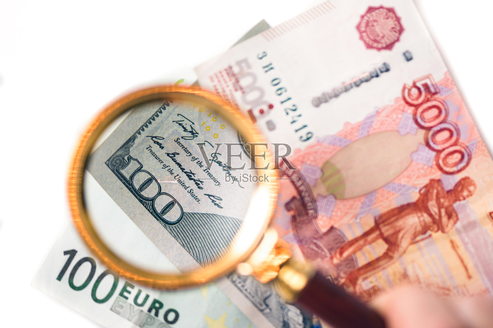 100美元在放大镜下的背景是欧元和卢布钞票。主要国际货币的概念照片摄影图片