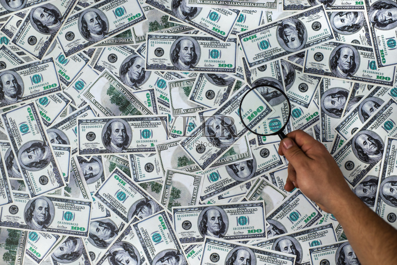 男子拿着放大镜,背景是一百美元照片摄影图片