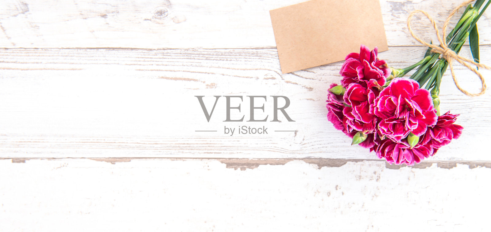 五月母亲节概念摄影-美丽的康乃馨与模板卡孤立在明亮的木桌上,复制空间,平铺,俯视图,模拟照片摄影图片