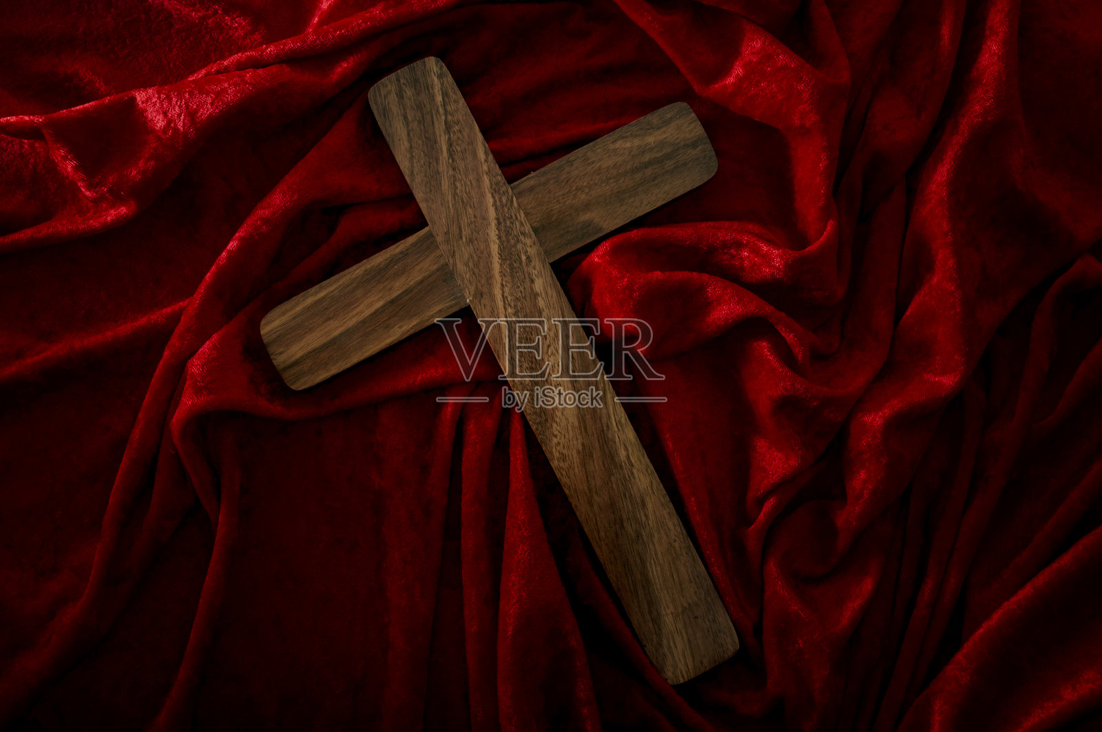 基督教,复活节假期和宗教信仰的概念与红色天鹅绒上的木十字架与波浪和皱纹与戏剧性的情绪化的光照片摄影图片