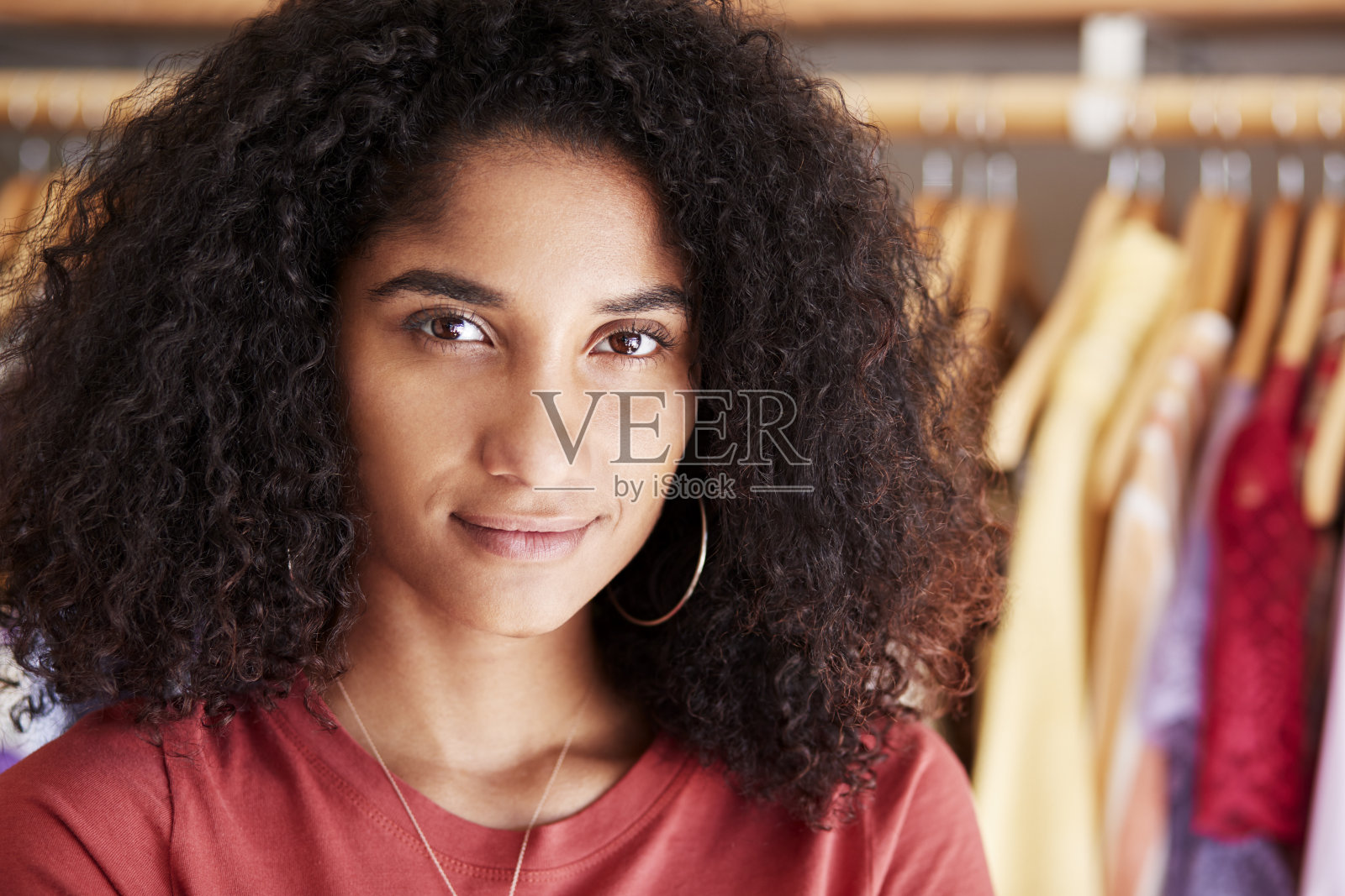 独立时装店女顾客或店主站在衣架旁的肖像照片摄影图片