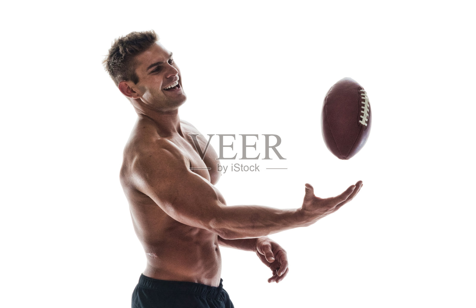 帅气的肌肉男拿着橄榄球照片摄影图片