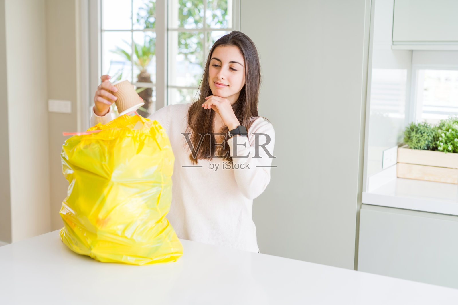 漂亮的年轻女子把垃圾从垃圾桶里拿出来严肃地面对思考问题,非常困惑的想法照片摄影图片