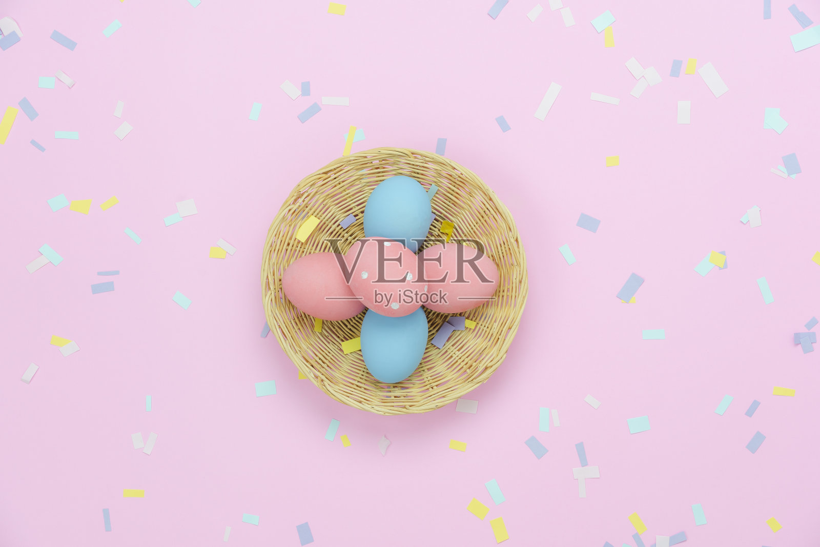 桌面视图拍摄的装饰复活节节日快乐的背景概念。平躺美丽的兔子蛋在木制篮子和五彩纸屑装饰派对节日在现代乡村粉纸墙纸。照片摄影图片