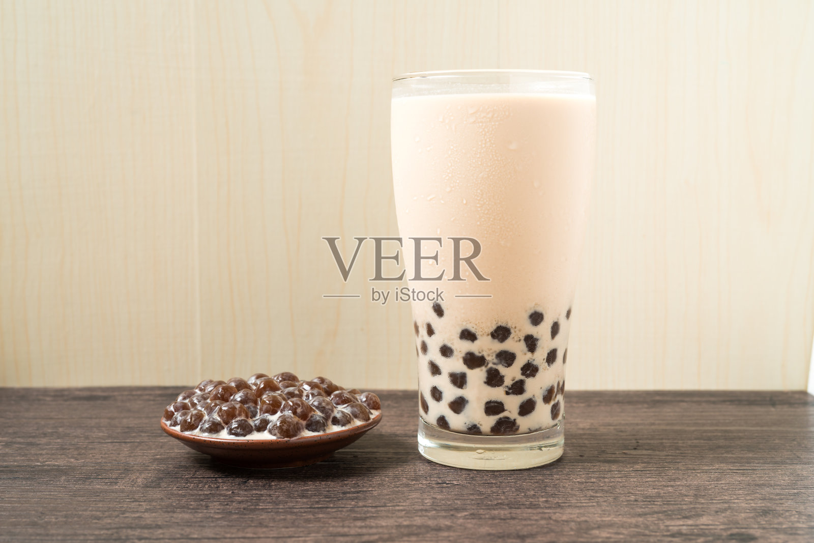 一杯珍珠奶茶(也叫珍珠奶茶)和一盘在木制背景上的木薯球。珍珠奶茶是台湾最具代表性的饮品。台湾的食物。与复制空间。照片摄影图片