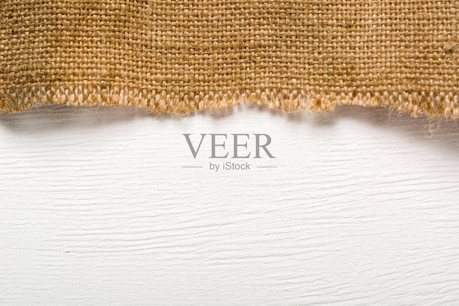 白木桌上放着一件粗麻布。为设计师做准备。有足够的空间放置文字和照片。照片摄影图片