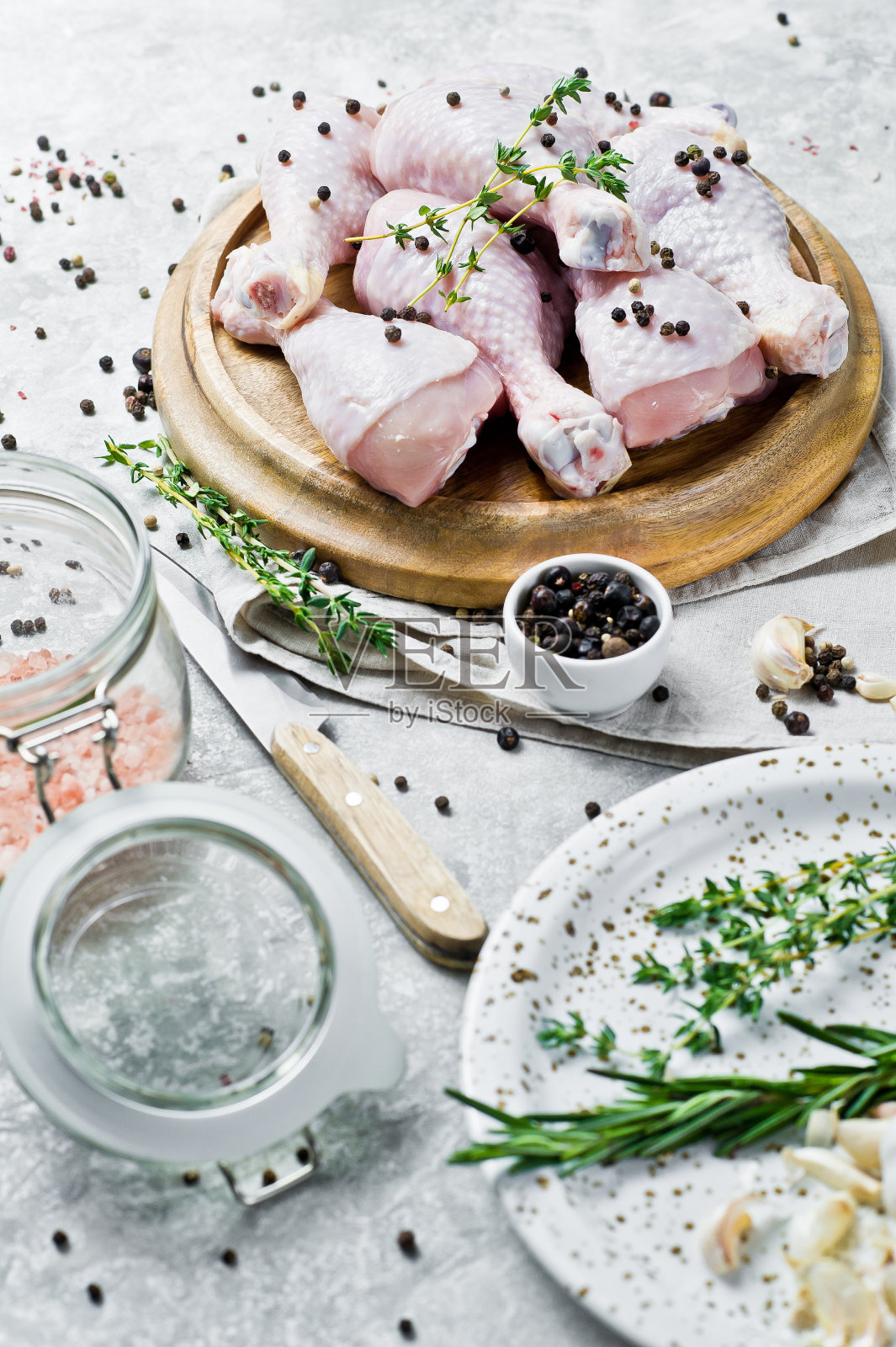 鸡腿。烹饪材料:迷迭香,百里香,大蒜,胡椒。灰色背景,侧视图。照片摄影图片