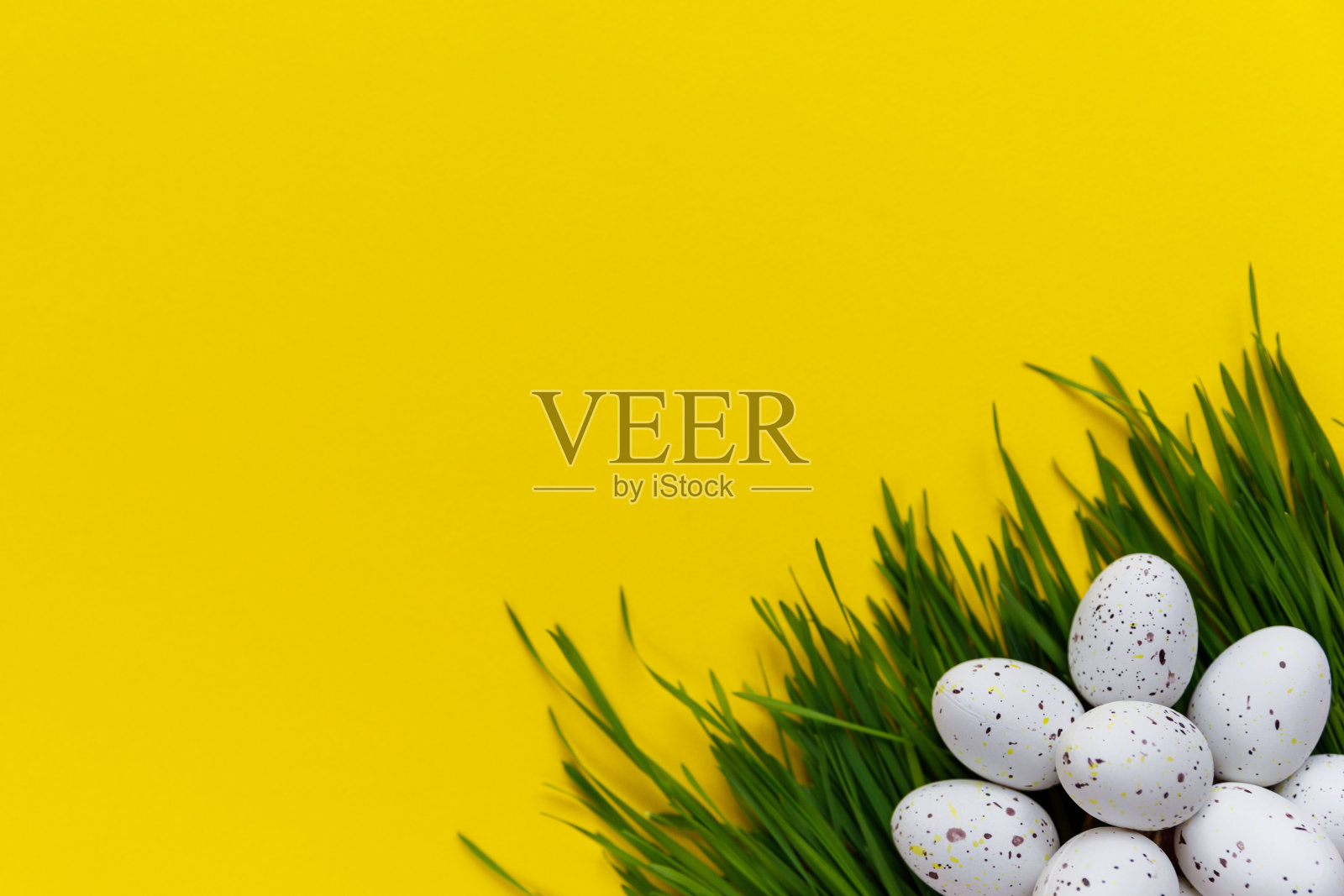 复活节装饰。装饰的鸡蛋和绿草放在黄色的背景上照片摄影图片