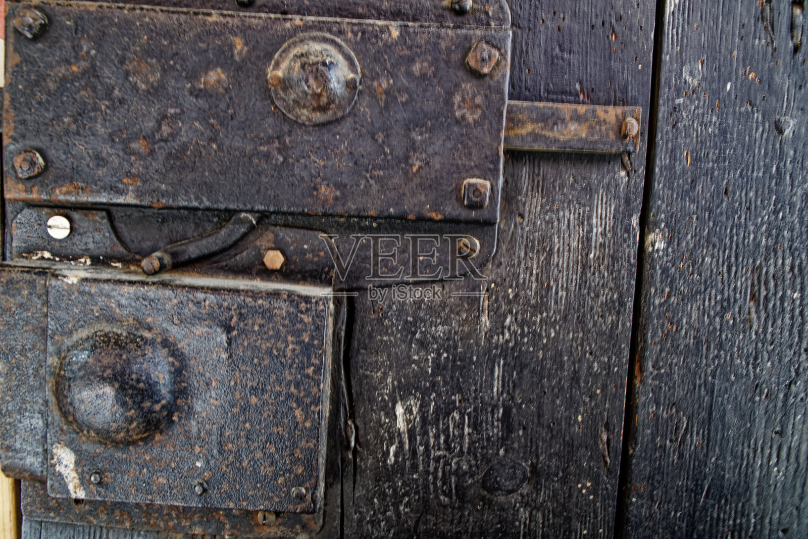 带有金属把手和生锈的中世纪门闩的旧木门。照片摄影图片