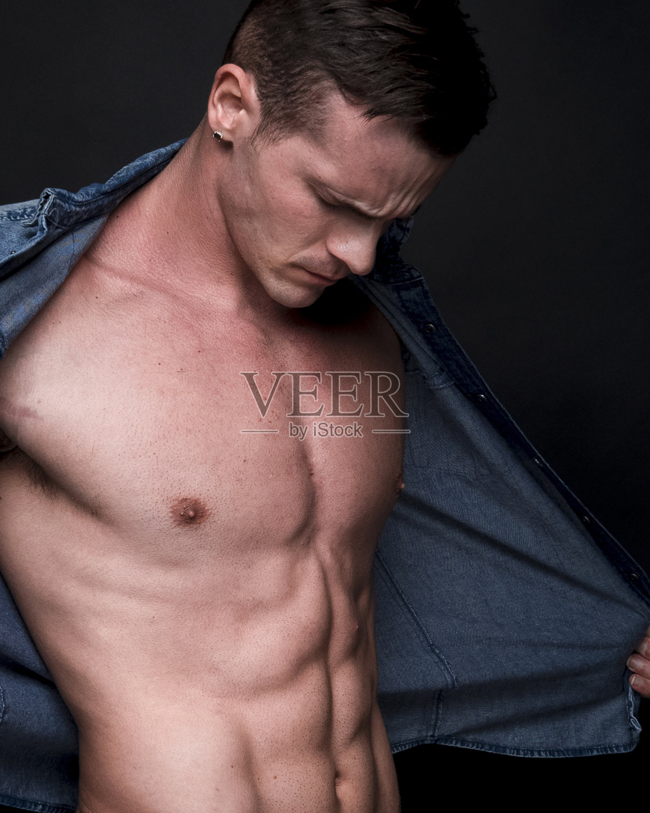 帅气的男性穿着一件解开的蓝色衬衫,感觉很性感照片摄影图片