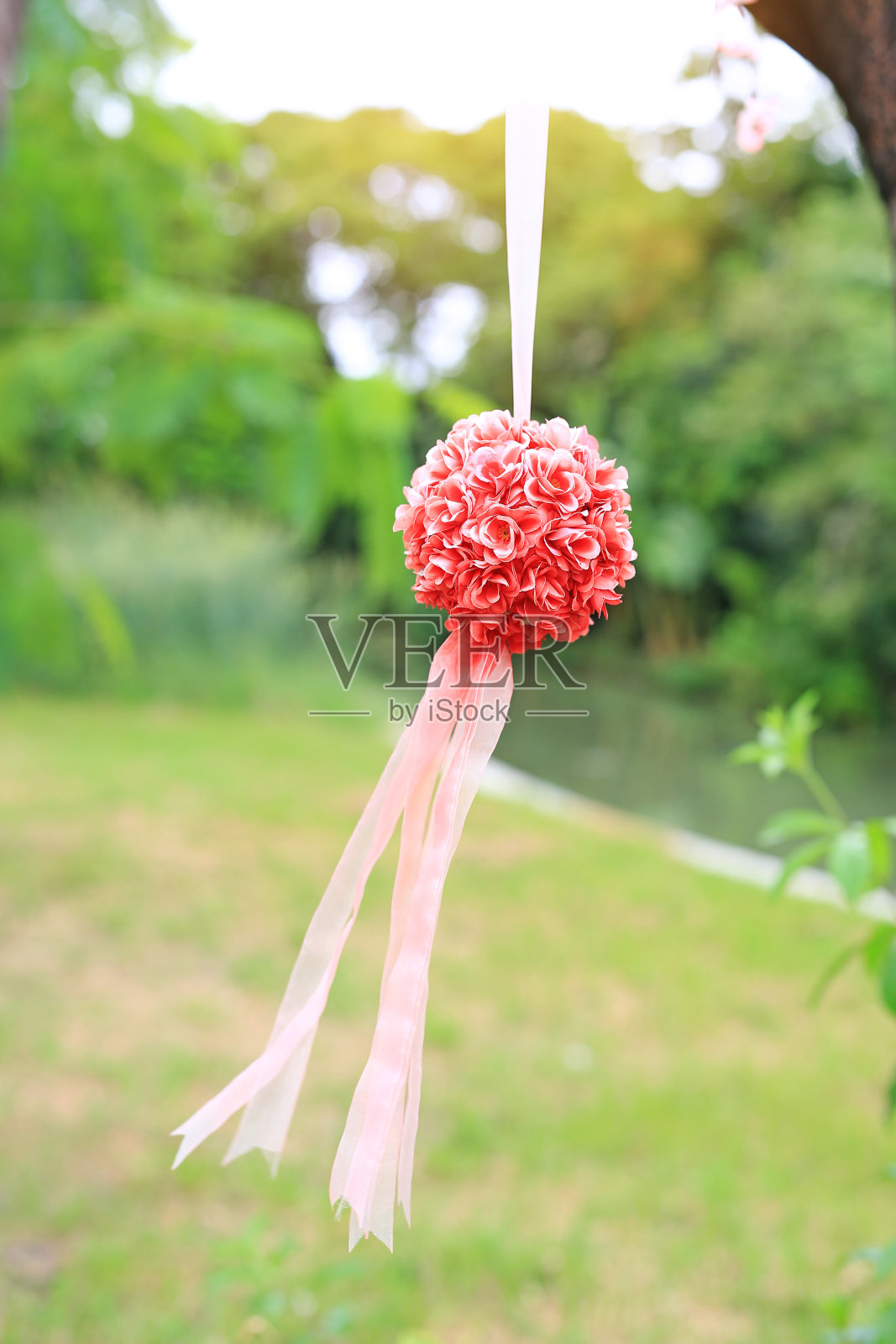 灌木装饰的人造玫瑰挂在自然公园。婚礼装饰在户外的绿色花园中。照片摄影图片