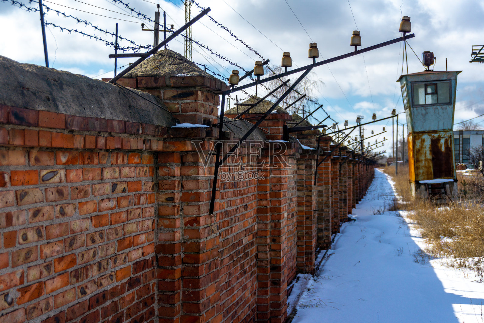 带带刺铁丝网的砖栅栏。照片摄影图片