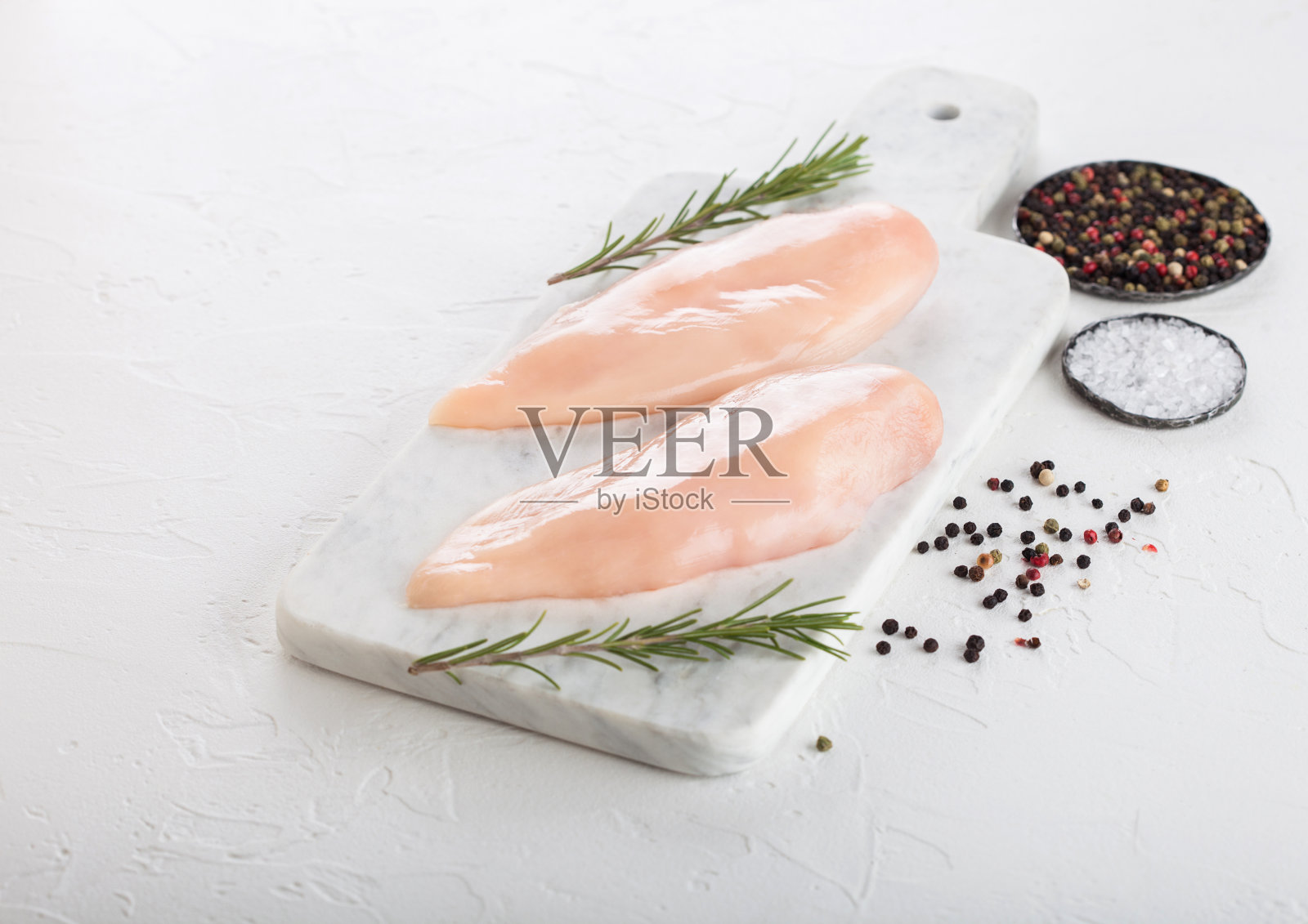 新鲜生有机鸡柳胸脯在白色大理石板与香料和香草在白色背景。照片摄影图片
