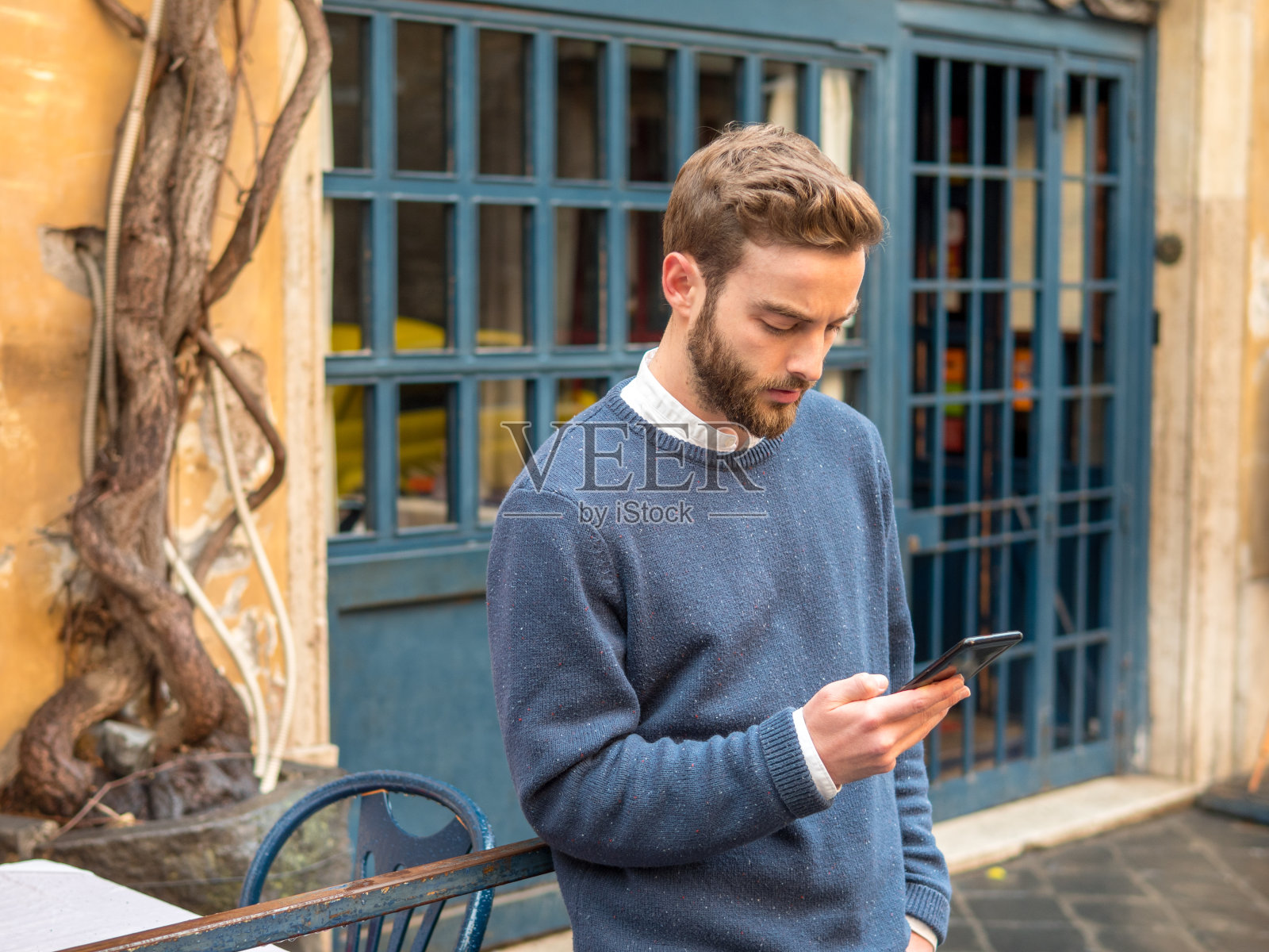 一位蓄着胡须的年轻男子仔细阅读着手机上的一条信息照片摄影图片