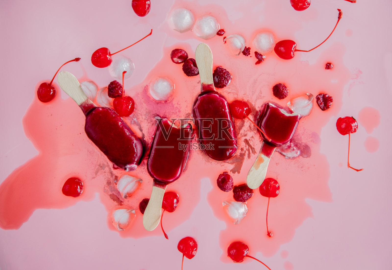 粉色背景上的覆盆子和樱桃冰棍照片摄影图片