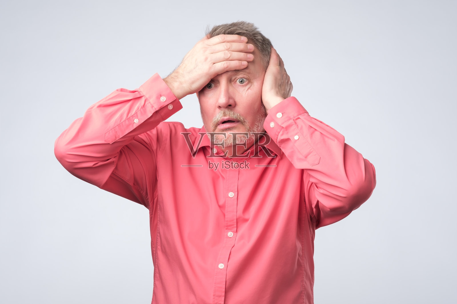 年长的白人惊讶地用手顶着头。照片摄影图片