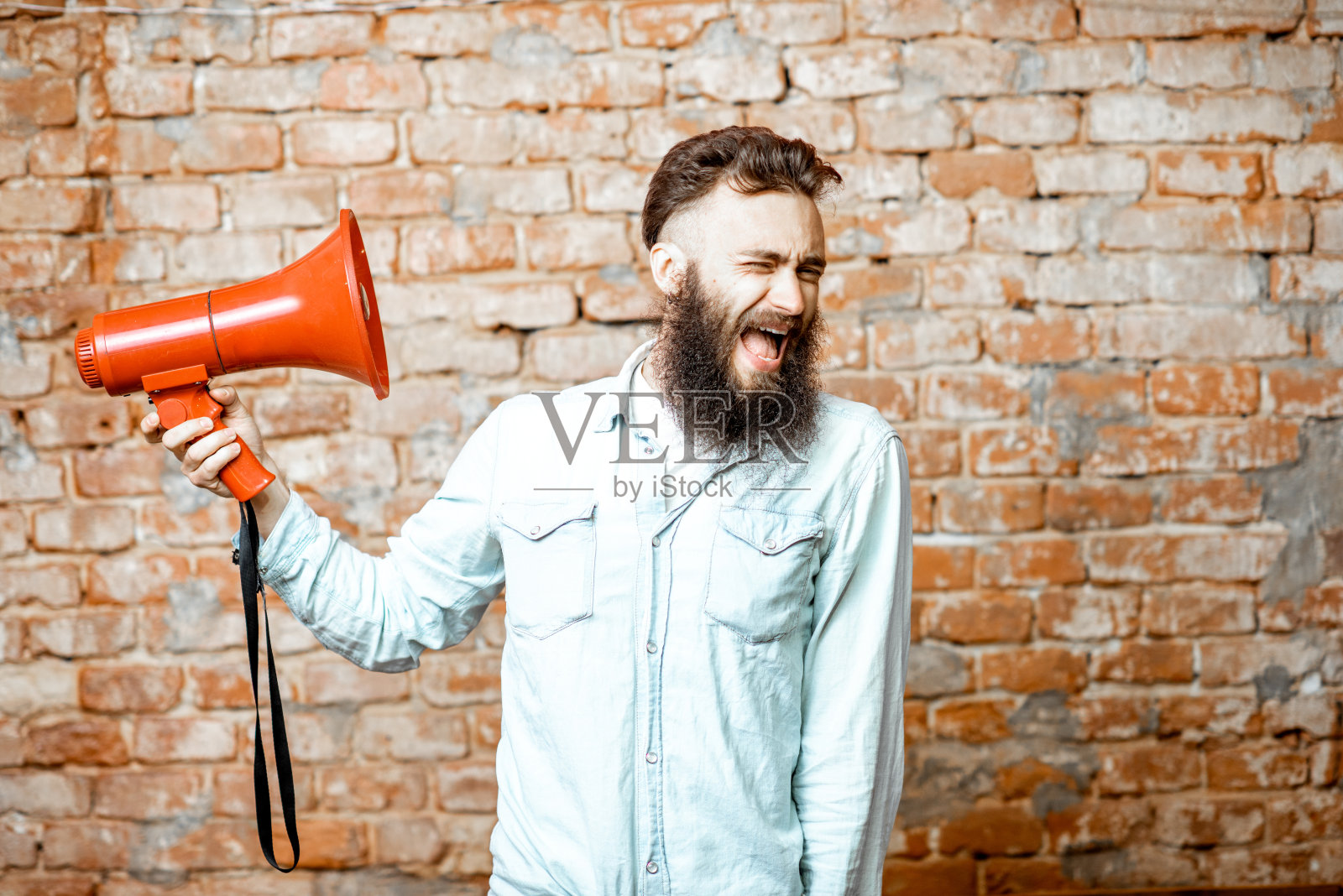 砖头背景上有个带扩音器的人照片摄影图片