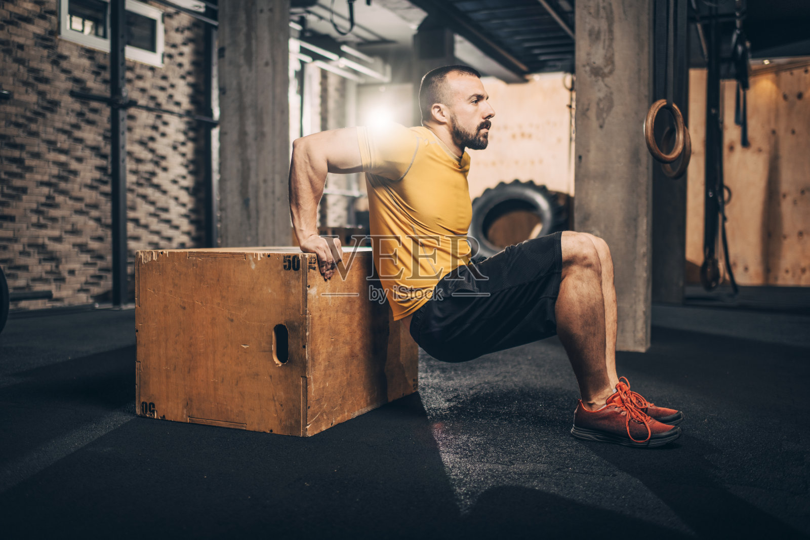 活跃的年轻男性运动员在健身房的板条箱上做下降运动照片摄影图片