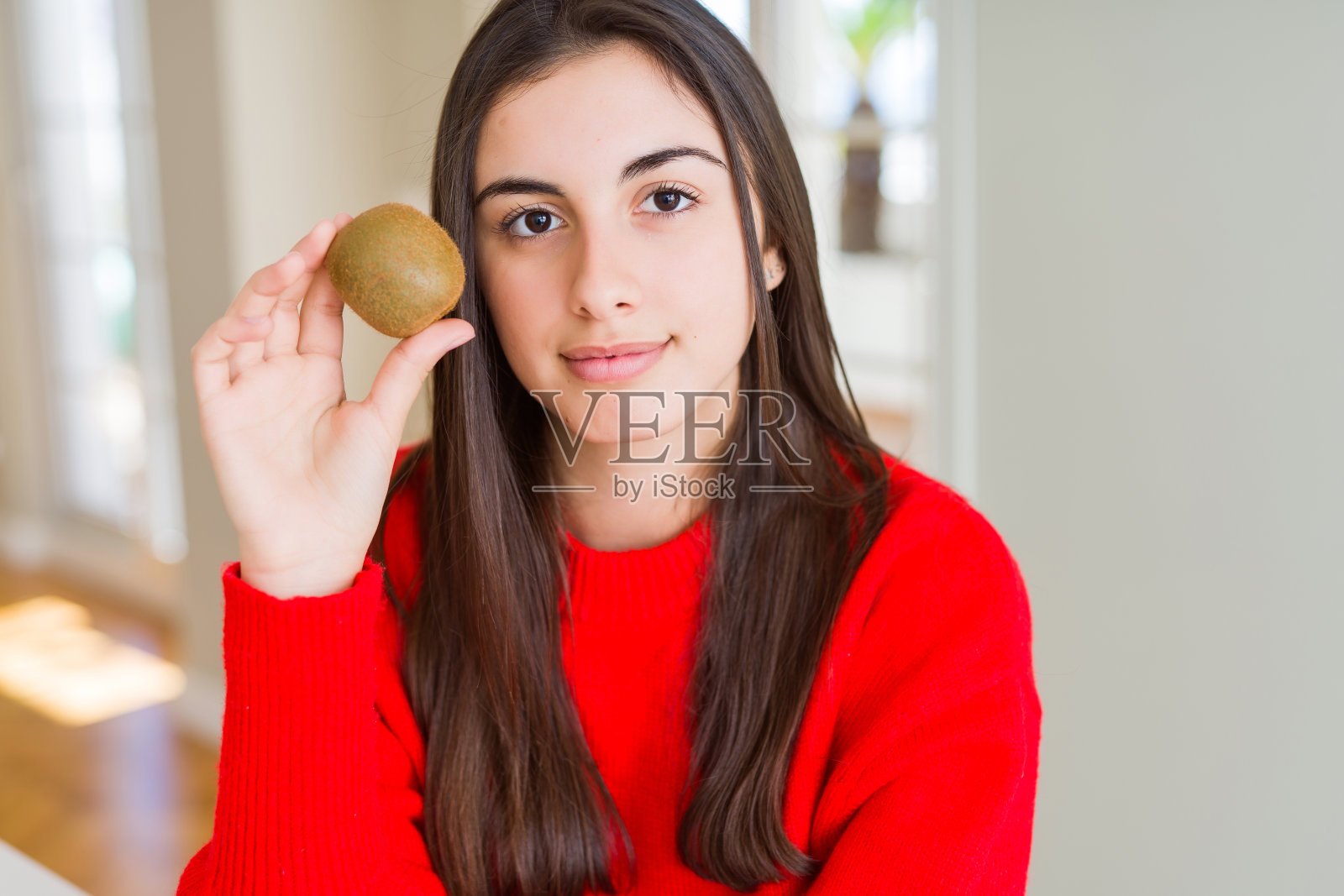 美丽的年轻女子吃新鲜的绿色猕猴桃,自信的表情,聪明的脸,思考认真照片摄影图片