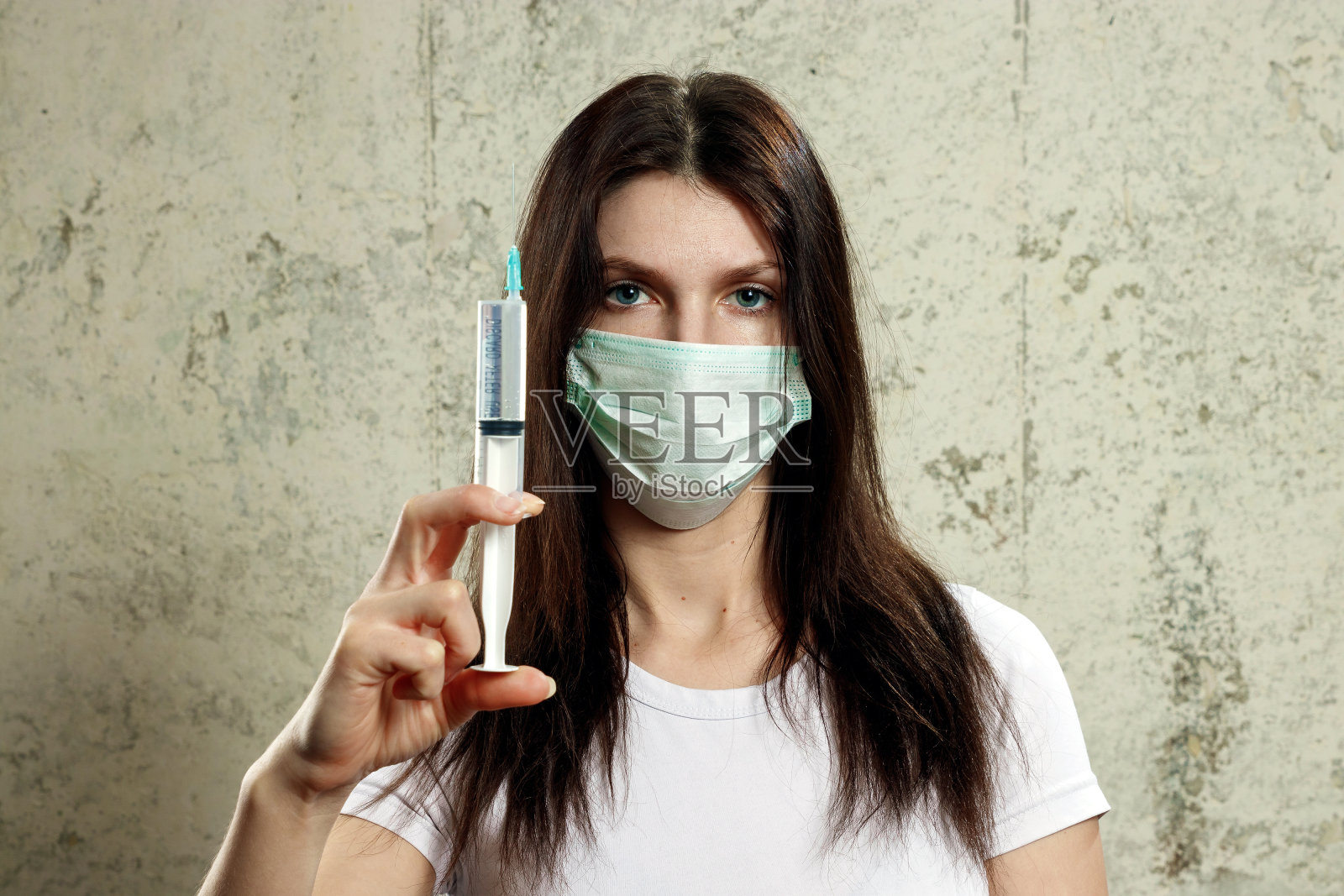 一个年轻,美丽,生病的女孩拿着注射器,戴着医用口罩的肖像。疾病的概念,流感,治疗,注射,免疫。照片摄影图片