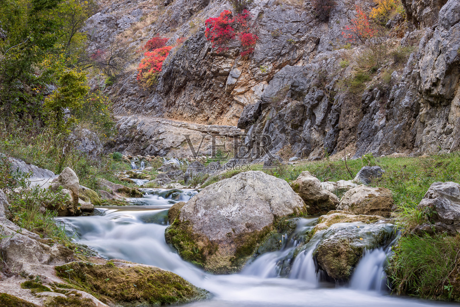 秋天的颜色在一个狭窄的峡谷和蓝色运动的山溪水照片摄影图片