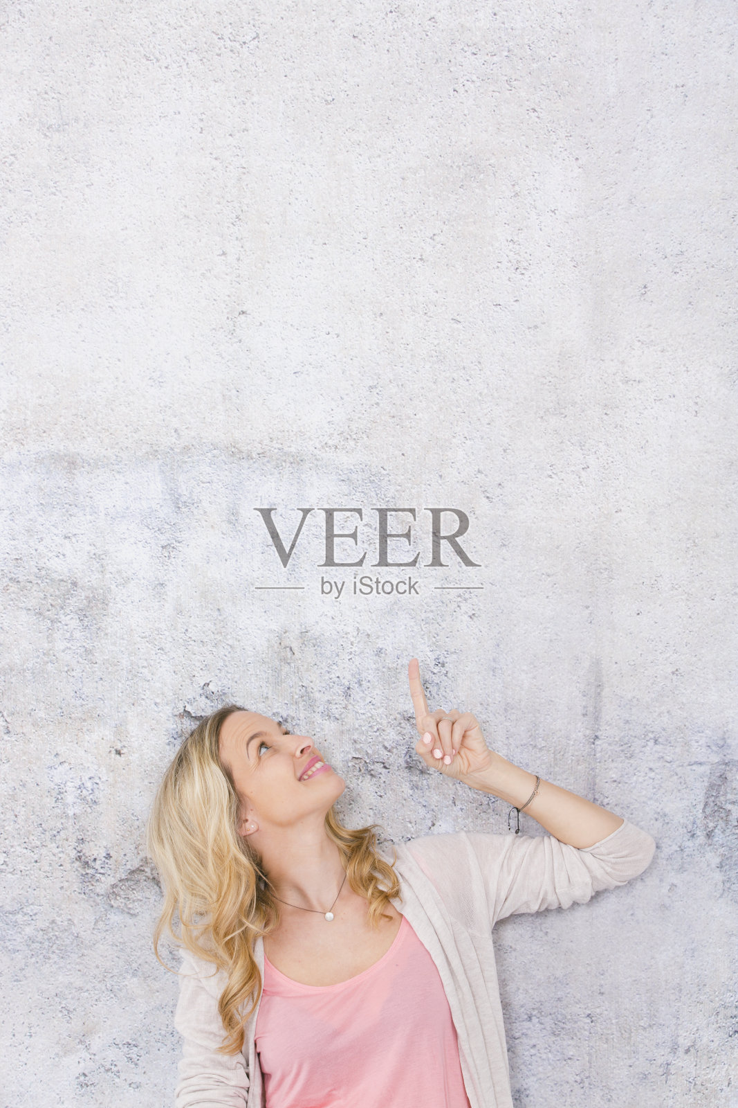 美丽的金发女人正在指着并摆姿势照片摄影图片