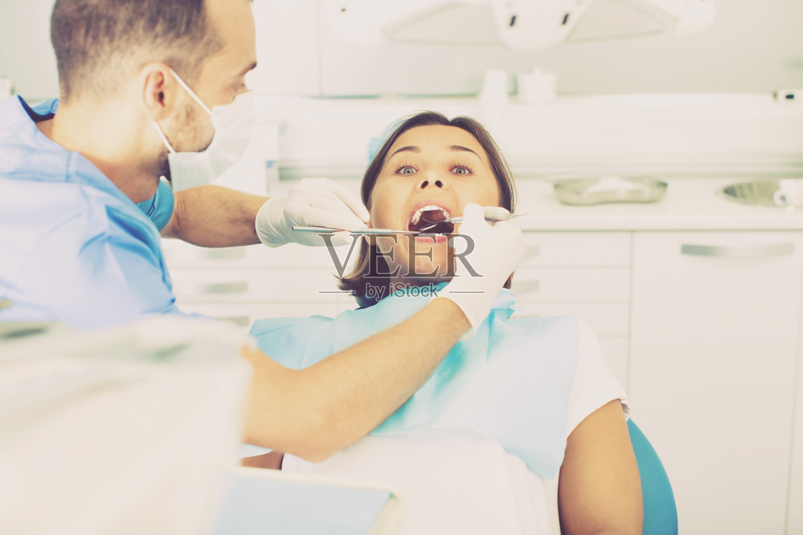 牙医正在治疗一位坐在牙科椅上的女病人照片摄影图片