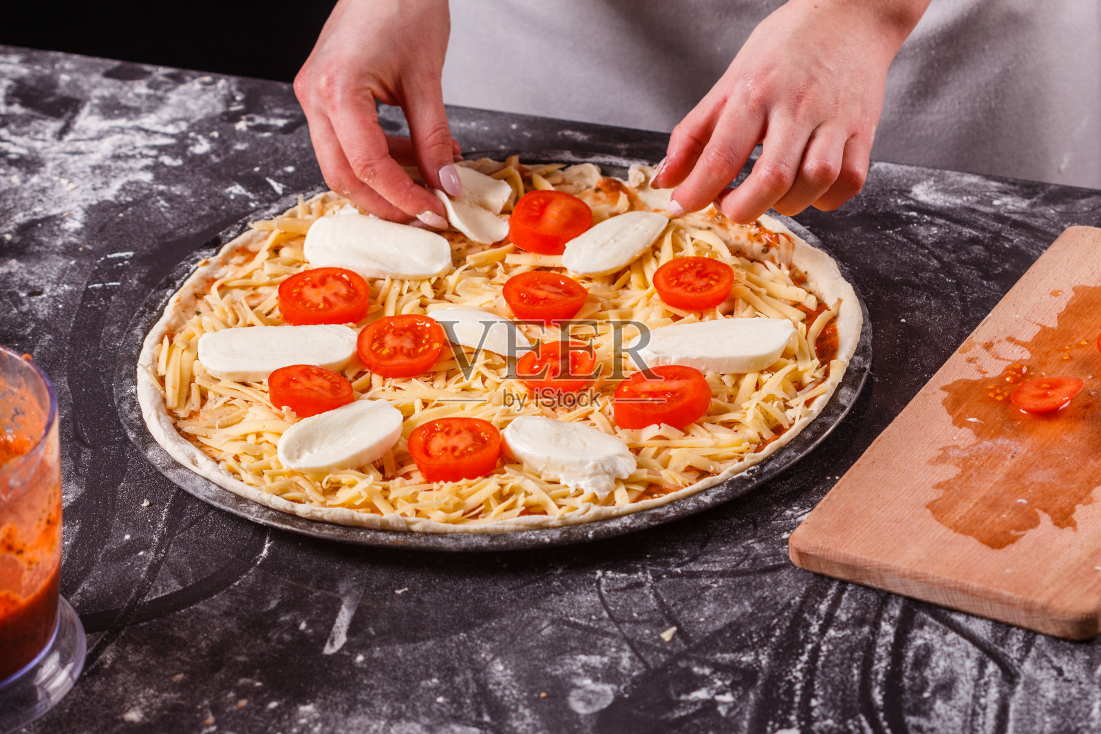 穿着灰色围裙的年轻女子准备了一杯玛格丽塔披萨照片摄影图片