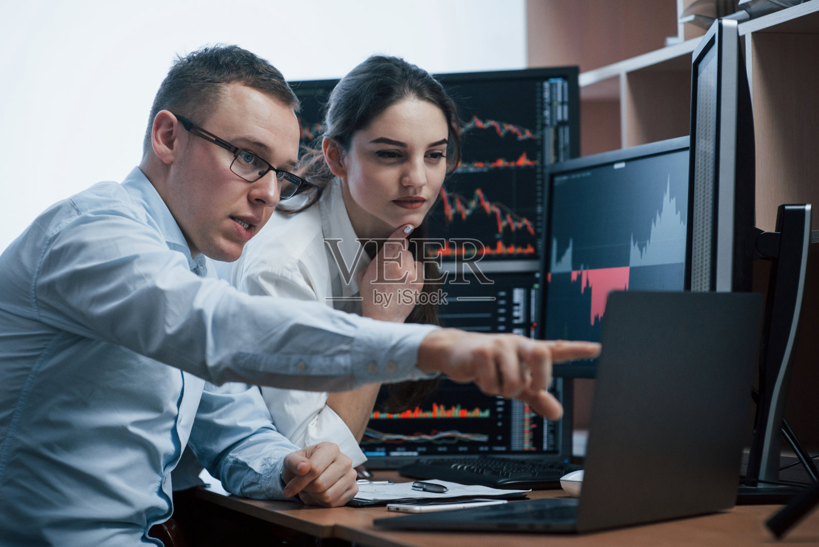 做出明智的决定。一组股票经纪人正在一间有多个显示屏的办公室里进行对话照片摄影图片