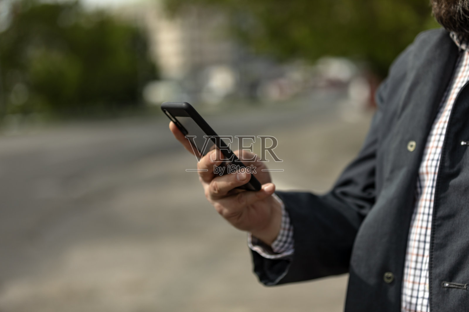 有吸引力的成熟商人穿着西装走在户外,用手机照片摄影图片
