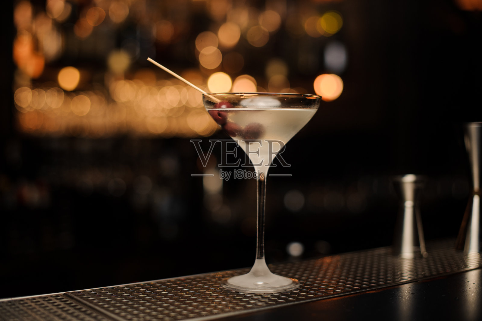 鸡尾酒放在冰冷的玻璃杯里,串上点缀着浆果照片摄影图片