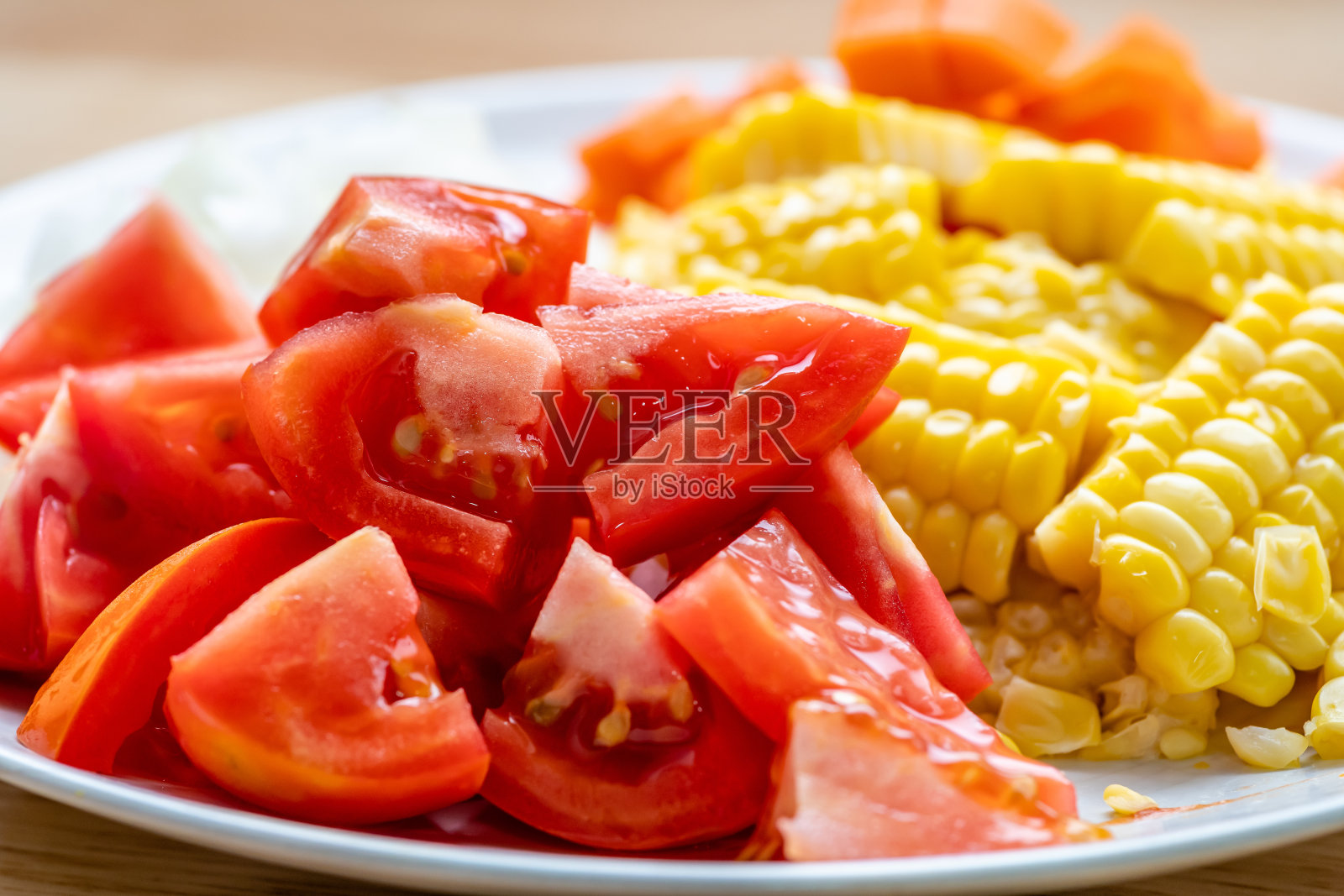 切片西红柿和玉米放在白盘子里照片摄影图片