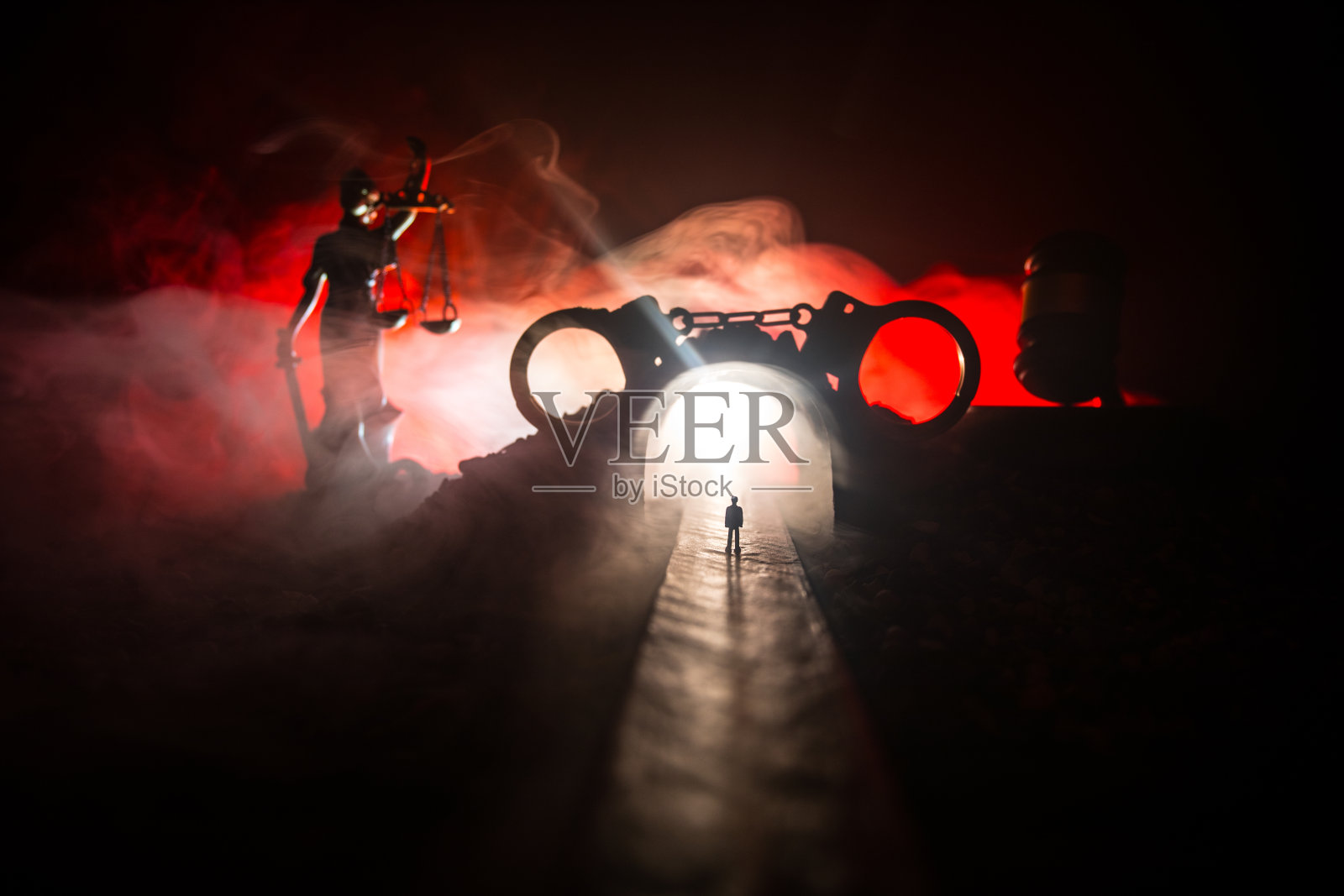 合法的法律概念。手铐的剪影与正义的雕像在背后与闪烁的红色和蓝色的警察灯在雾蒙蒙的背景。有选择性的重点照片摄影图片