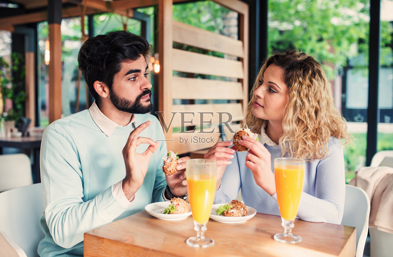 一对年轻漂亮的夫妇坐在咖啡馆里吃早餐。爱情,约会,食物,生活理念照片摄影图片